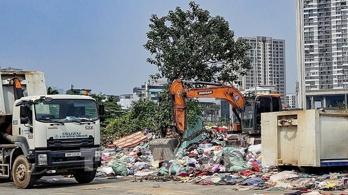 Lực lượng vệ sinh môi trường huy động phương tiện cơ giới thu gom lượng lớn quần áo cũ tồn đọng tại phường Từ Liêm (Hà Nội). Ảnh: Trung Nguyên - TTXVN.