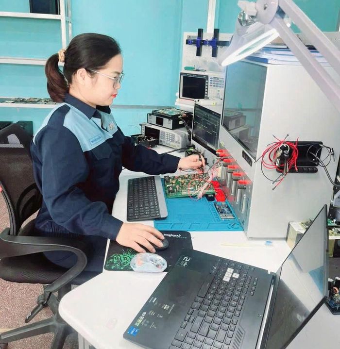 Nữ nhân viên kỹ thuật thuộc Phân xưởng 5 đang thực hiện viết bài test cho mạch điện tử trên máy ATK.