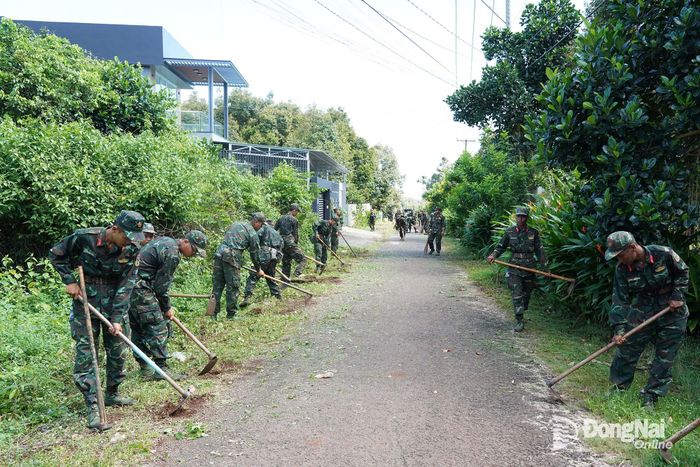 Cán bộ, chiến sĩ Trung đoàn 88, Sư đoàn 302 tham gia dọn dẹp vệ sinh môi trường, chỉnh trang tuyến đường số 15, khu phố Xuân Tân, phường Hàng Gòn. Ảnh: Thanh Tú