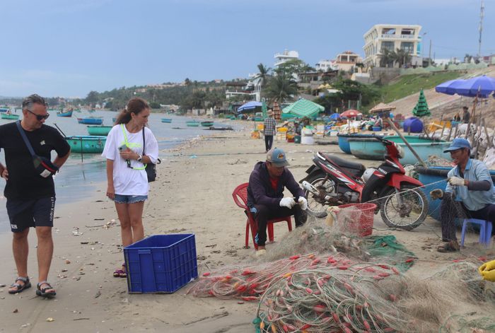 Du khách xem ngư dân gỡ cá sau khi thuyền cập bến