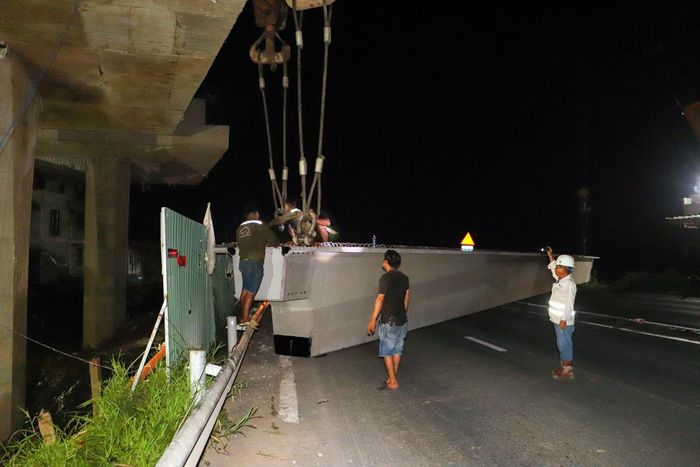 Dưới sự phối hợp nhịp nhàng của các thiết bị cẩu chuyên dụng, phiến dầm nặng khoảng 75 tấn từ từ được nâng khỏi xe vận chuyển, đưa lên cao để chuẩn bị di chuyển vào vị trí lắp đặt.