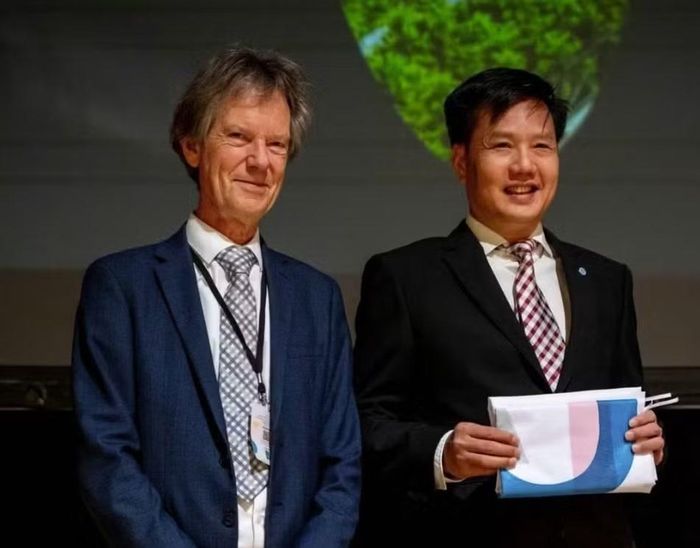  Ông John Shawe-Taylor, Chủ tịch IAIO kiêm Giám đốc Trung tâm Nghiên cứu quốc tế về trí tuệ nhân tạo (IRCAI) trao cờ đăng cai IAIO 2027 cho đại diện Việt Nam, ông Nguyễn Hoàng Giang, Viện trưởng Viện Nghiên cứu Đổi mới sáng tạo và Kiểm định chất lượng (RIVA) tại IAIO 2026. 