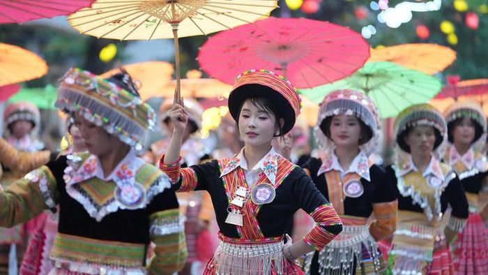 Các cô gái Thái duyên dáng trong trang phục thổ cẩm truyền thống, tay cầm ô diễu diễn rộn ràng trên đường phố Nghĩa Lộ.