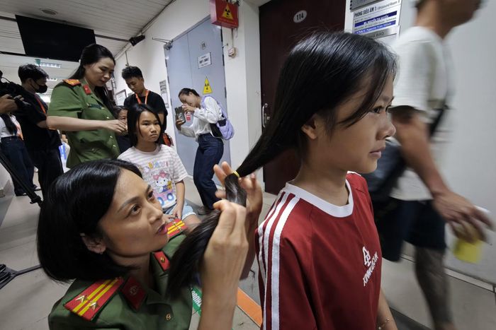 Trung tá Nguyễn Thu Hằng làm tình nguyện viên, con gái và cháu gái của chị cùng hiến tóc.