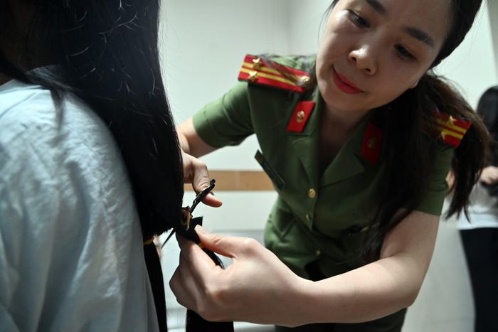 Lưỡi kéo đi sát sợi chun để lọn tóc giữ nguyên nếp. Hành động được cán bộ Công an Thủ đô làm chậm, tỉ mỉ, tránh để hỏng lọn tóc