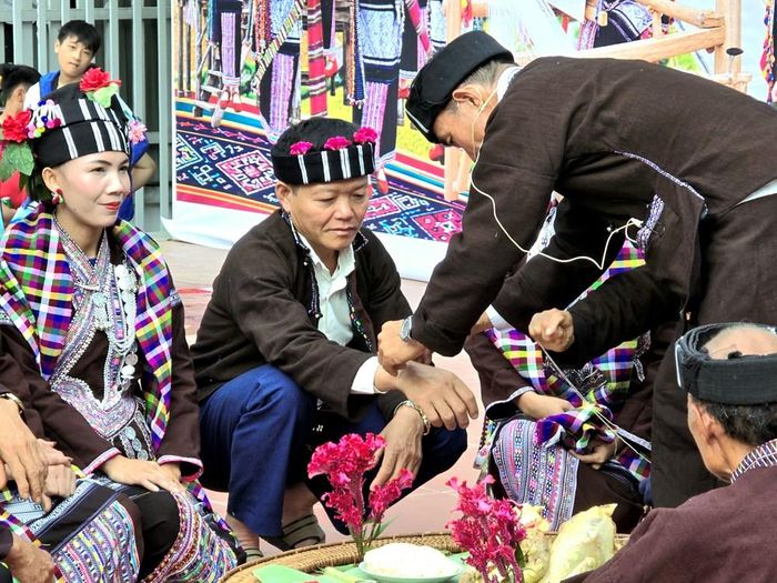 Thầy cúng buộc chỉ cổ tay cho chủ trâu nhằm giữ chặt hồn, cầu chúc sức khỏe