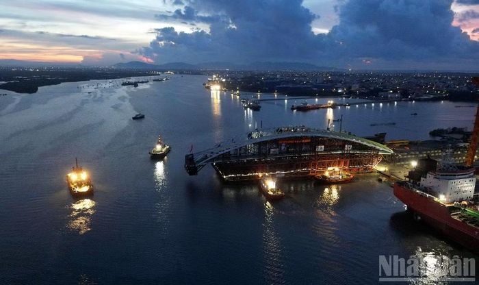 Khối vòm thép đang nằm trên sà lan ở cảng lúc rạng sáng. Chung quanh là các tàu kéo, tàu lai dắt chuẩn bị vào tác nghiệp. (Ảnh: Lê Đình Thìn)