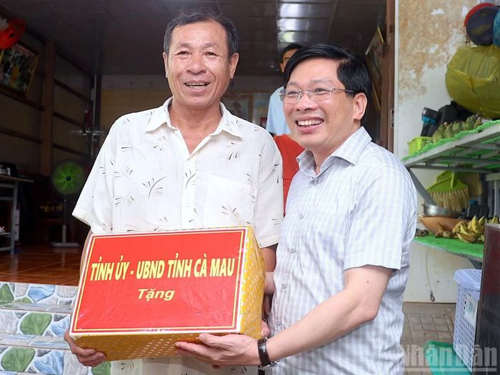 Phó Bí thư Thường trực Tỉnh ủy Cà Mau Đặng Văn Dũng (bên phải) thay mặt đoàn công tác tặng quà cho hộ dân trên địa bàn xã Đất Mũi, tỉnh Cà Mau. (Ảnh: HỮU TÙNG)