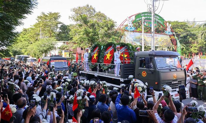 Đông đảo người dân cầm hoa trắng, cờ Tổ quốc đứng dọc đường tiễn đưa các liệt sĩ