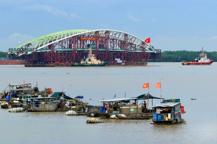  Sà lan chở nhịp chính cầu đi bộ qua sông Sài Gòn được các tàu lai dắt qua khu vực ghe thuyền neo đậu trên sông Soài Rạp, chiều 18-10. Ảnh: HOÀNG HÙNG 