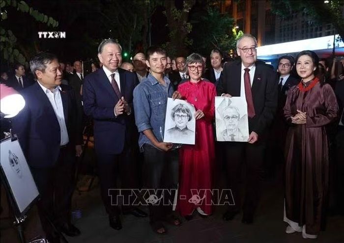 Hoạ sĩ trên phố đi bộ hồ Hoàn Kiếm (Hà Nội) tặng Tổng thống Thụy Sĩ Guy Parmelin và Phu nhân 2 bức ký hoạ chân dung, tối 17/10/2026. Ảnh: Thống Nhất/TTXVN