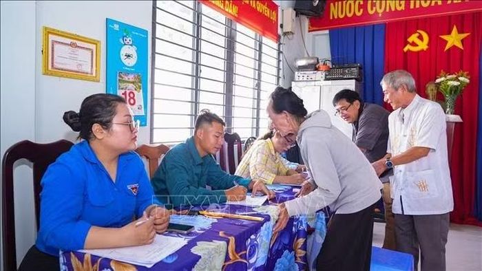 Thành viên tổ bầu cử hướng dẫn, hỗ trợ cử tri thực hiện các thủ tục tại điểm bầu cử khu phố 11, phường Tân Ninh, tỉnh Tây Ninh. Ảnh: Minh Phú/TTXVN