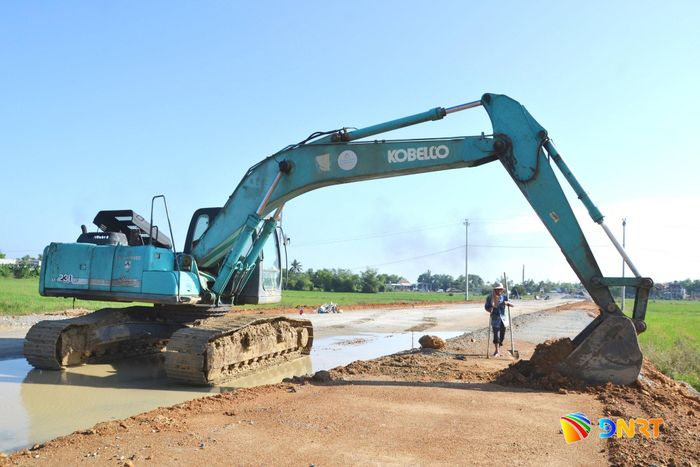 Vét rãnh thoát nước đọng trên nền đường đang thi công (đoạn qua xã Thăng Điền) do trận mưa tối 16/10 gây ra. Ảnh: CÔNG TÚ