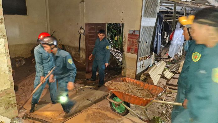 Lực lượng dân quân thuộc Ban CHQS xã dọn dẹp giúp các hộ dân bị đất, đá tràn vào nhà