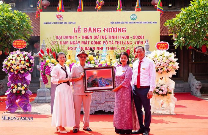 Nhiếp ảnh gia, Kỷ lục gia Vũ Hải trao bức tranh tượng Phật tặng Ban Quản lý di tích Côn Sơn - Kiếp Bạc. Ảnh: Tuấn Anh.