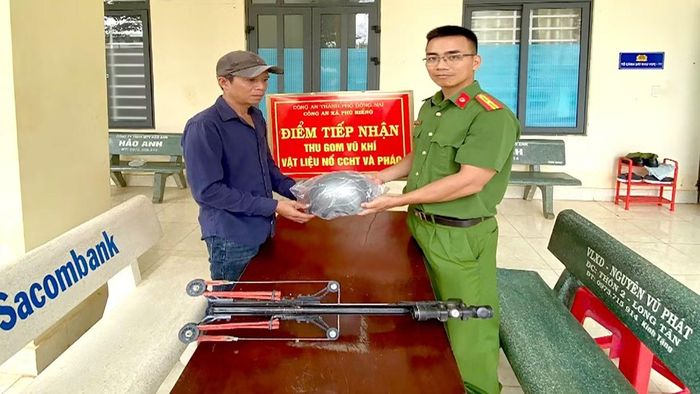 Cán bộ Công an xã Phú Riềng tiếp nhận vũ khí giao nộp và tặng mũ bảo hiểm cho người dân .
