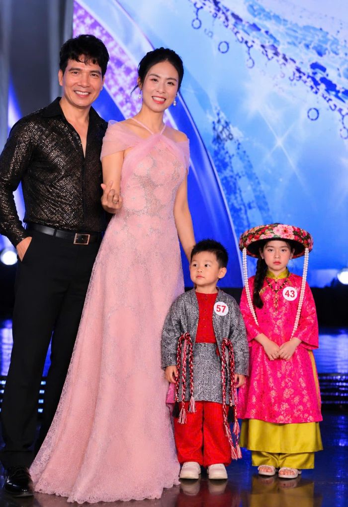 Ca sĩ Hồ Quang 8 và Hoa hậu Ngọc Hân giao lưu cùng các mẫu nhí tại Vietkids Junior Fashion Week 2026. Hai mẫu nhí trong trang phục truyền thống tạo điểm nhấn cho khoảnh khắc giao lưu trên sân khấu.