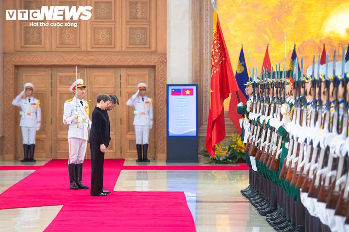 Thủ tướng Lê Minh Hưng và Thủ tướng Liechtenstein Brigitte Haas cúi chào Quân kỳ Quyết thắng của Quân đội Nhân dân Việt Nam.