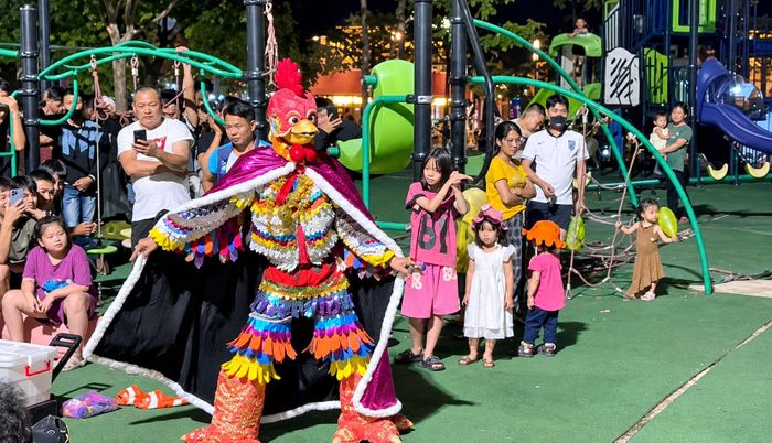 Một người hóa trang thành nhân vật gà, mặc trang phục sặc sỡ và biểu diễn tại khu vực sân chơi công viên Lãm Làng. (Ảnh cắt từ clip)