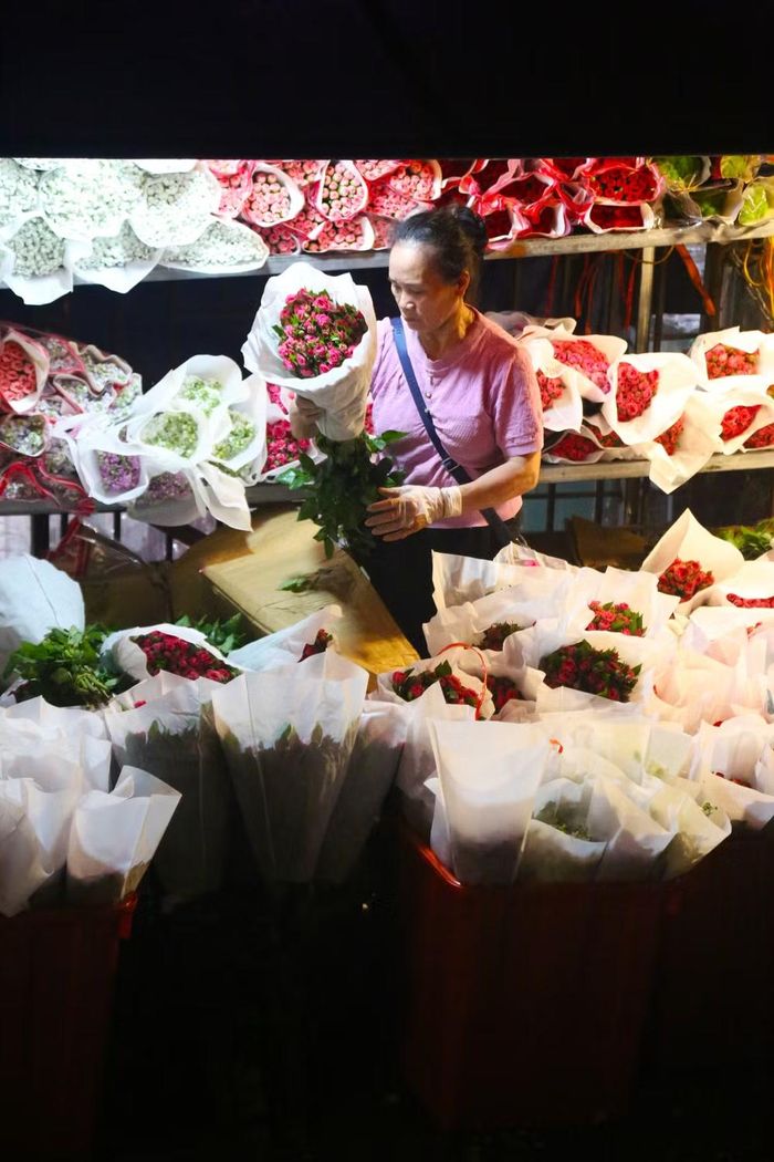 Người bán tỉ mỉ kiểm tra chất lượng, chăm chút từng bó hoa hồng và bọc giấy gói hoa cẩn thận trước khi bày bán