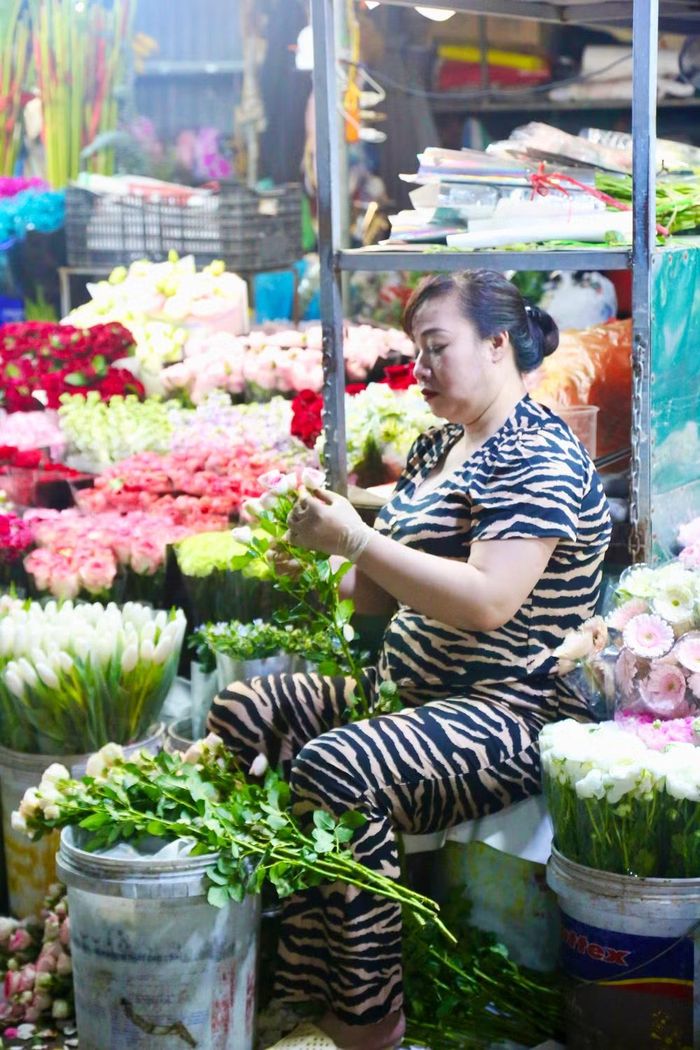 Qua đôi bàn tay đeo găng khéo léo của người tiểu thương, từng chiếc lá hỏng được bỏ đi, những cành hoa hồng được chỉnh trang tỉ mỉ, nổi bật giữa muôn vàn sắc hoa