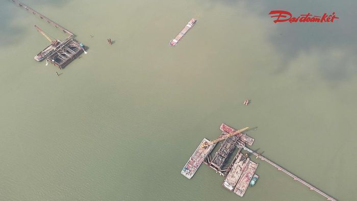 Trên công trường, hệ thống máy móc và sà lan được huy động phục vụ thi công dưới lòng sông. Các công đoạn được triển khai nối tiếp nhằm bảo đảm điều kiện thi công và tiến độ của những hạng mục tiếp theo.
