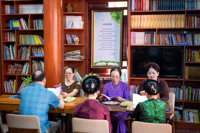  Các thành viên trong nhóm sinh hoạt ca trù của bà Khanh cùng nhau đọc sách 15 phút trước giờ tập văn nghệ. 
