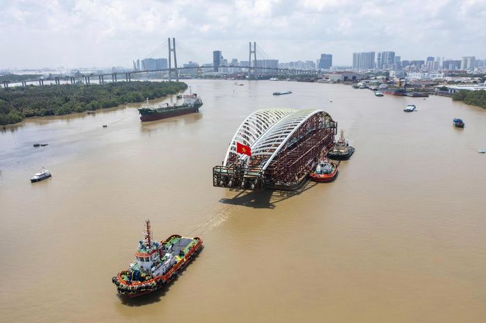 Khối vòm thép hình lá dừa nước nổi bật giữa sông Sài Gòn, được các tàu phối hợp lai dắt, điều chỉnh hướng di chuyển.
