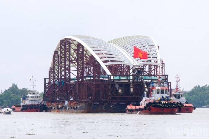 Sà-lan chở nhịp vòm thép cầu đi bộ mang hình dáng lá dừa nước tiếp tục hành trình, di chuyển qua khu vực bán đảo Kim Cương, Thành phố Hồ Chí Minh.
