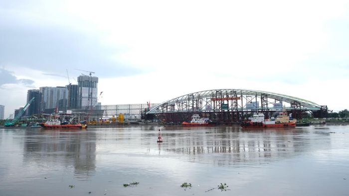Đến khoảng 15 giờ cùng ngày, nhịp cầu đi bộ lá dừa nước nặng 3.400 tấn vượt qua cầu Phú Mỹ, tiếp tục hành trình trên sông Sài Gòn hướng về bến Bạch Đằng, nơi công trình sẽ được tập kết, chờ công tác hợp long.