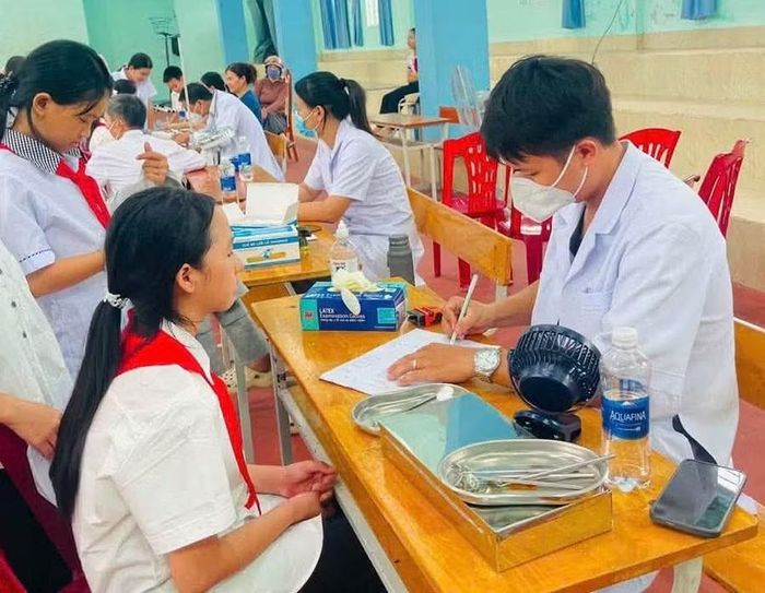 Cán bộ y tế cơ sở khám sức khoẻ cho học sinh.