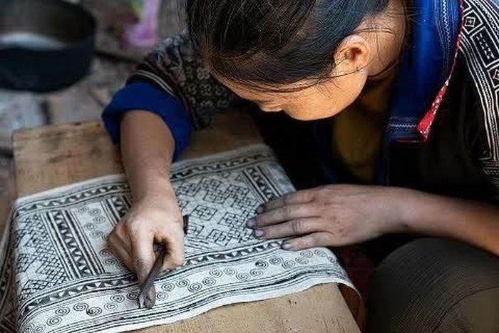 Các nghệ nhân và đồng bào Mông giới thiệu những công đoạn làm nên tấm vải lanh, từ xe sợi, dệt vải đến nhuộm chàm và vẽ sáp ong. (Ảnh: Việt Hoàng)