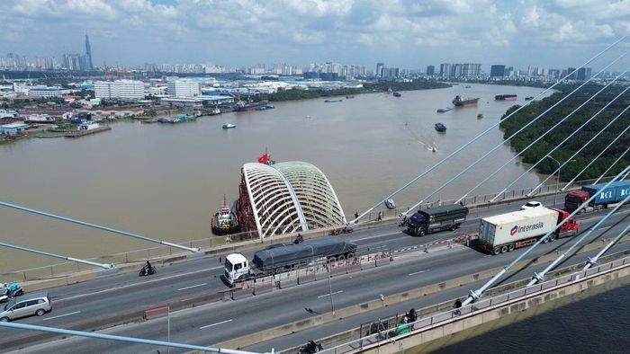 Đến khoảng 10h23, siêu sà lan chở vòm thép cùng đoàn tàu lai dắt tiến qua cầu Phú Mỹ