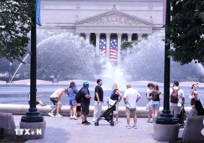 Người dân tránh nắng nóng bên đài phun nước tại khu vực National Mall (Quảng trường Quốc gia) ở thủ đô Washington D.C. (Ảnh: Ngọc Quang/TTXVN)