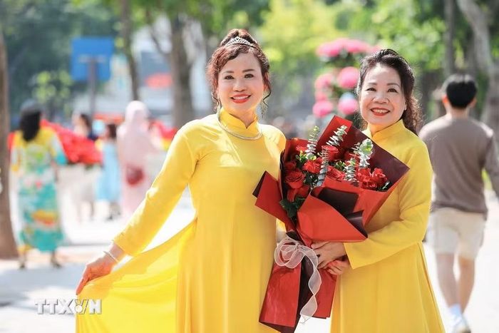 Phụ nữ cùng áo dài truyền thống tạo nên nét duyên dáng giữa không gian xanh mát bên hồ Hoàn Kiếm. (Ảnh: Lê Đông/TTXVN)