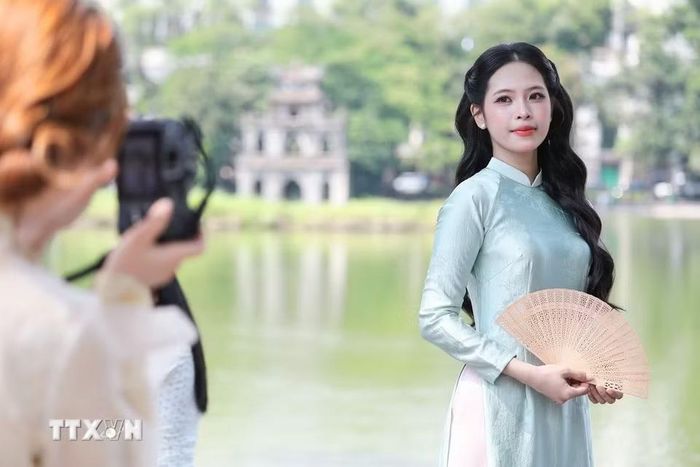 Người dân, du khách tranh thủ ghi lại những kỷ niệm đẹp bên hồ Hoàn Kiếm nhân Ngày Phụ nữ Việt Nam 20/10. (Ảnh: Lê Đông/TTXVN)