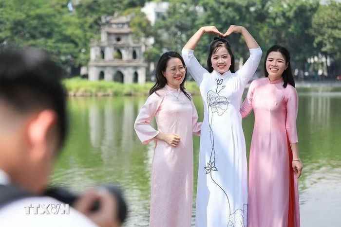 Áo dài truyền thống tạo nên nét duyên dáng giữa không gian xanh mát bên hồ Hoàn Kiếm. (Ảnh: Lê Đông/TTXVN)