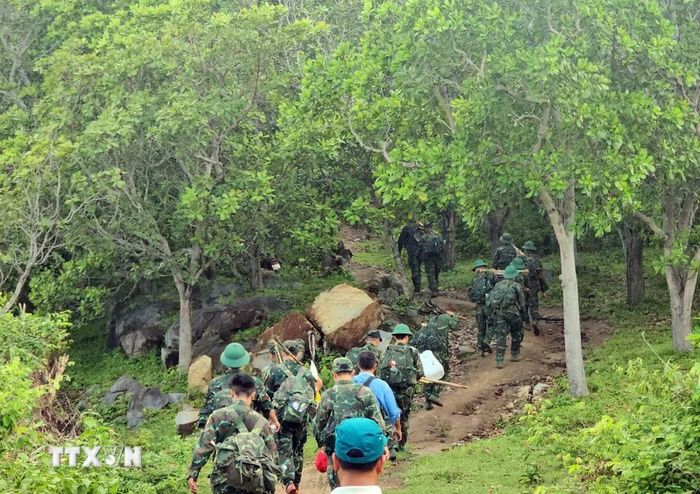 Các chiến sỹ leo núi tìm đến điểm cao 700, khu vực Đá Bò (xã Công Hải) để cất bốc, quy tập hài cốt liệt sỹ. (Ảnh: Công Thử/TTXVN)