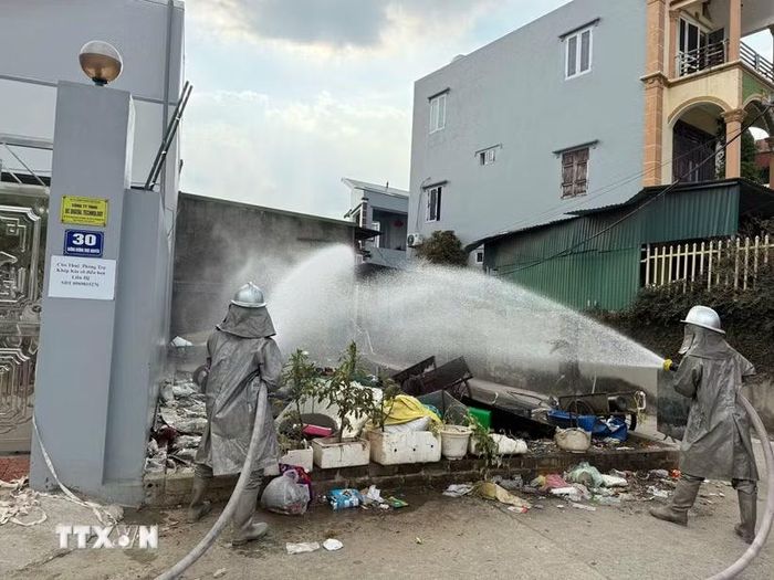 Cán bộ, chiến sỹ Đội Chữa cháy và Cứu nạn, cứu hộ khu vực số 32 triển khai phun nước xử lý sự cố rò rỉ khí clo tại thôn Mễ Sơn, xã Thượng Phúc. (Ảnh: TTXVN phát)