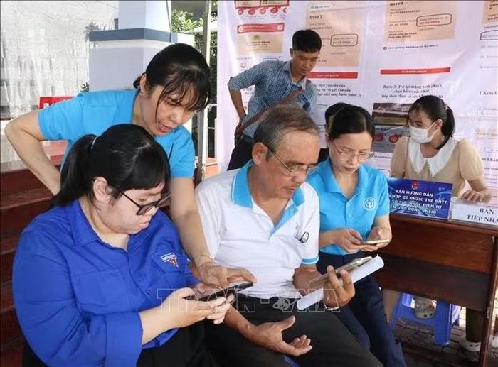 Đoàn viên, thanh niên phường Vị Tân và cán bộ Bảo hiểm xã hội cơ sở Vị Tân hướng dẫn người dân tích hợp sổ BHXH, thẻ BHYT và Sổ sức khỏe điện tử lên VNeID. Ảnh: Duy Khương/TTXVN