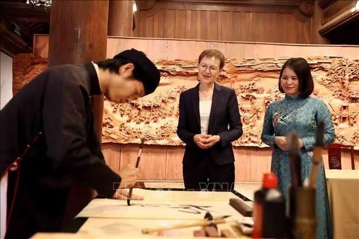 Thủ tướng Liechtenstein Brigitte Haas xem viết thư pháp tại Văn Miếu - Quốc Tử Giám. Ảnh: An Đăng/TTXVN