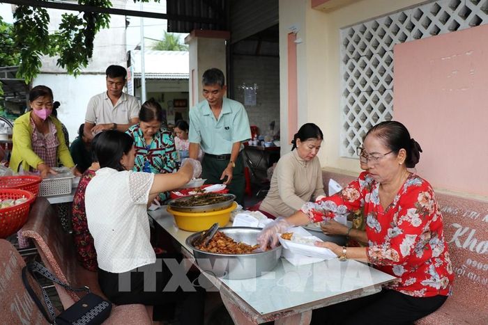 Cô Lâm Thị Cúc Huỳnh (bên phải) cùng các thành viên bếp “Cơm chay không đồng Chủ nhật” chia thức ăn, chuẩn bị trao cho người dân có hoàn cảnh khó khăn. Ảnh: Thanh Hòa - TTXVN