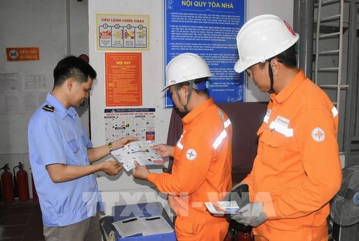 Cán bộ điện lực tuyên truyền cho người dân về những nguy cơ cháy nổ. Ảnh: Quốc Lũy - TTXVN 