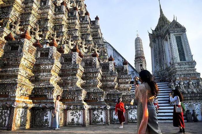 Du khách từ Trung Quốc mặc trang phục truyền thống Thái Lan tham quan chùa Wat Arun, Bangkok. Ảnh: Reuters