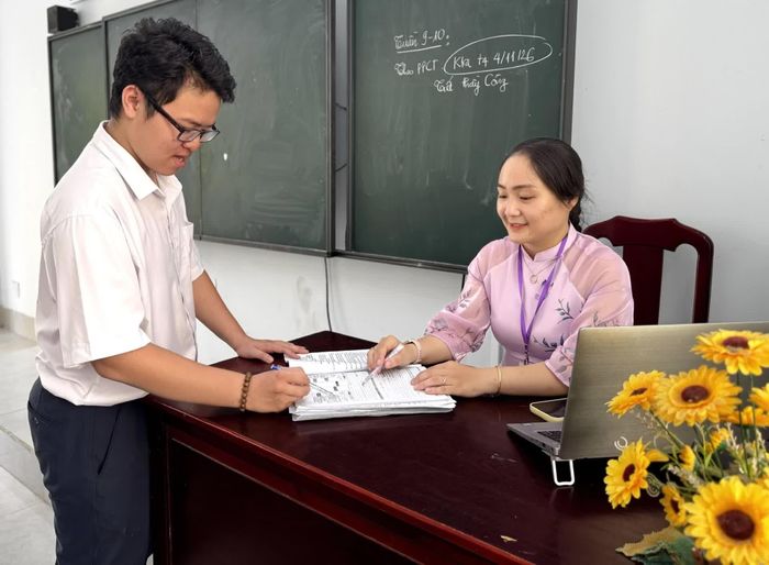 Gia Bảo và giáo viên trao đổi bài tập trong một giờ học.