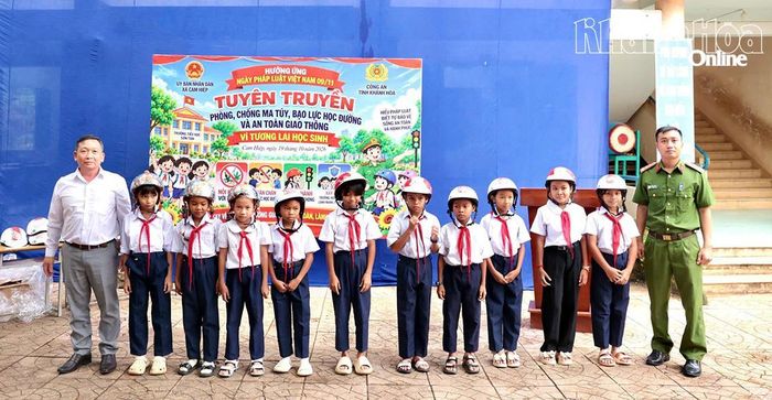 Lãnh đạo xã Cam Hiệp, đại diện Phòng Cảnh sát điều tra tội phạm về ma túy Công an tỉnh trao mũ bảo hiểm cho các em học sinh.