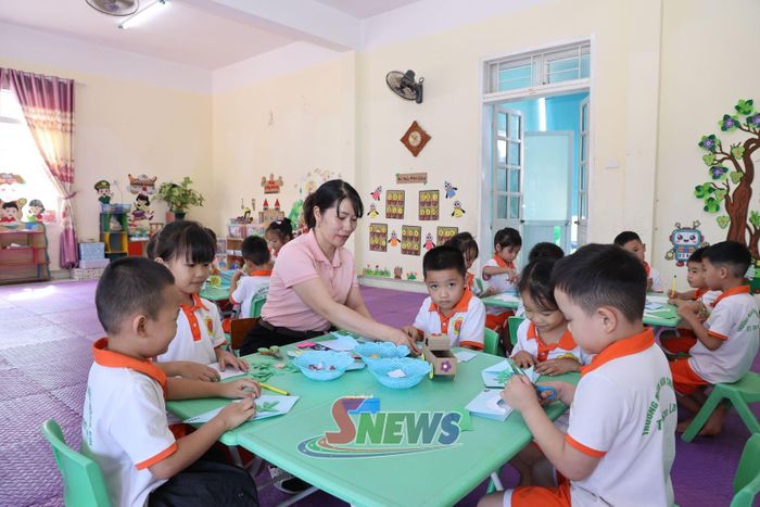 Giáo viên mầm non hướng dẫn trẻ làm đồ chơi.