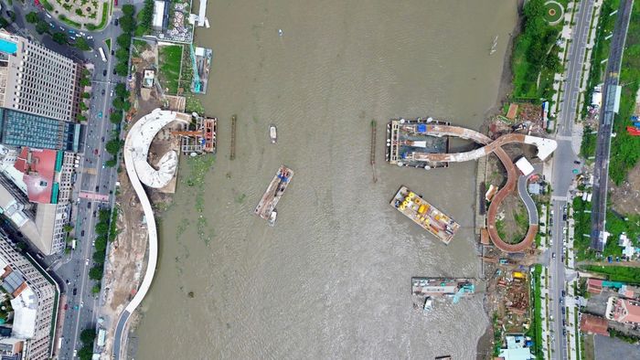 Tại khu vực giữa sông, công tác chuẩn bị đón nhịp chính được triển khai song song với việc hoàn thiện các hạng mục ở hai bờ. Khi sà lan chở kết cấu thép cập bờ Thủ Thiêm, các đơn vị sẽ tiến hành định vị, căn chỉnh để phục vụ công đoạn lắp đặt, kết nối nhịp cầu. Theo kế hoạch, công trình dự kiến hợp long ngày 21/10, đánh dấu bước tiến quan trọng trong quá trình thi công cầu đi bộ qua sông Sài Gòn.