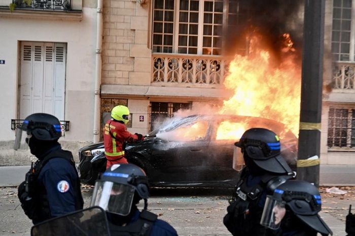 Một lính cứu hỏa nỗ lực dập tắt đám cháy tại chiếc ô tô trên đường phố Paris (Pháp). Ảnh: Bộ Nội vụ Pháp
