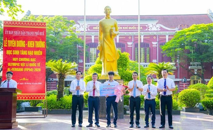Lãnh đạo thành phố Huế trao thưởng và tặng hoa chúc mừng em Tăng Hạo Nhiên, học sinh đoạt Huy chương Bạc tại Kỳ thi Olympic Vật lý quốc tế Al-Fergani (FIPhO) năm 2026. Ảnh: hue.gov